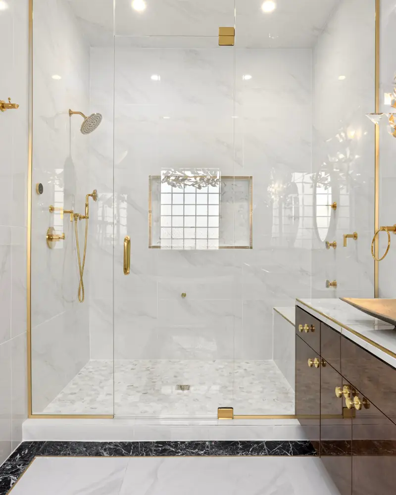 Polished bathroom with a glass shower, gold fixtures and a clean vanity after a detailed cleaning