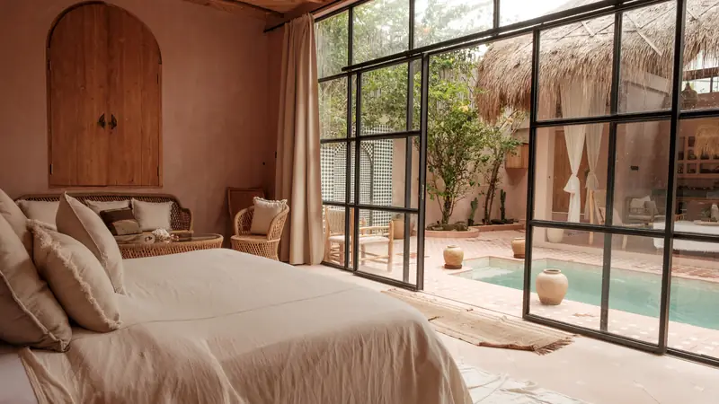 Calm, freshly made bedroom opening onto a sunny patio